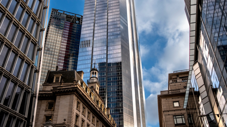 The image showcases a city scene where tall, reflective skyscrapers tower above a historic building, highlighting the intersection of modern innovation and classic architecture  in London UK