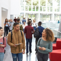 Students holding tablets and phone talk in university lobby