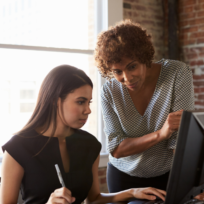 Two Businesswomen Working On Computer In Office