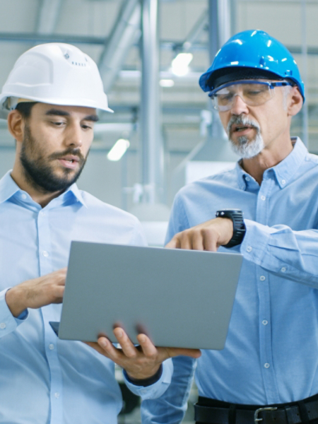 Head of the Project Holds Laptop and  Discusses Product Details with Chief Engineer while They Walk Through Modern Factory.