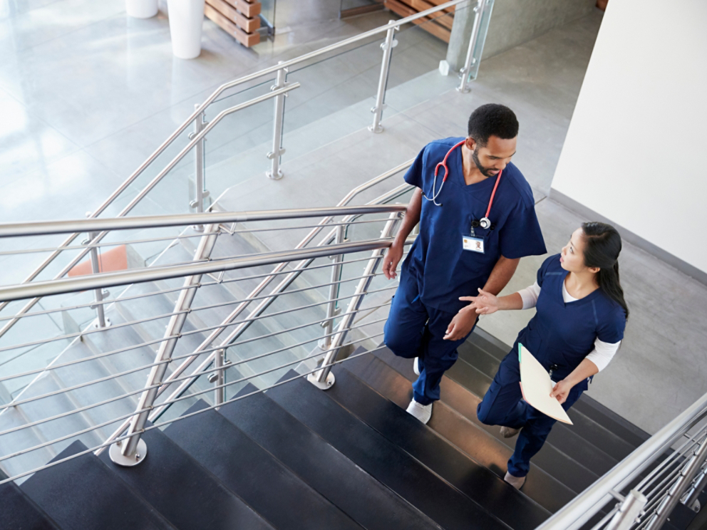 Two healthcare colleagues talking on the stairs at hospital