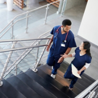 Two healthcare colleagues talking on the stairs at hospital