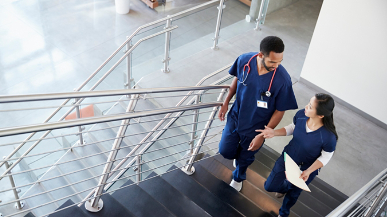 Two healthcare colleagues talking on the stairs at hospital