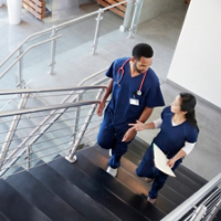 Two healthcare colleagues talking on the stairs at hospital