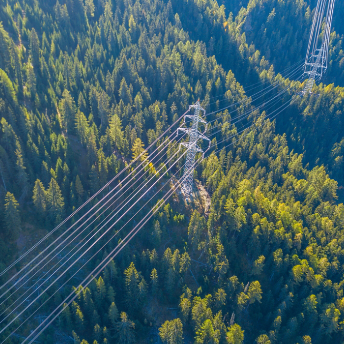 Aerial view of power line pylon in mountaineous area in Switzerland through valley in Canton of Valais