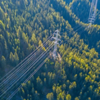 Aerial view of power line pylon in mountaineous area in Switzerland through valley in Canton of Valais