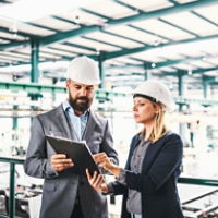 A portrait of an industrial man and woman engineer with clipboard in a factory.