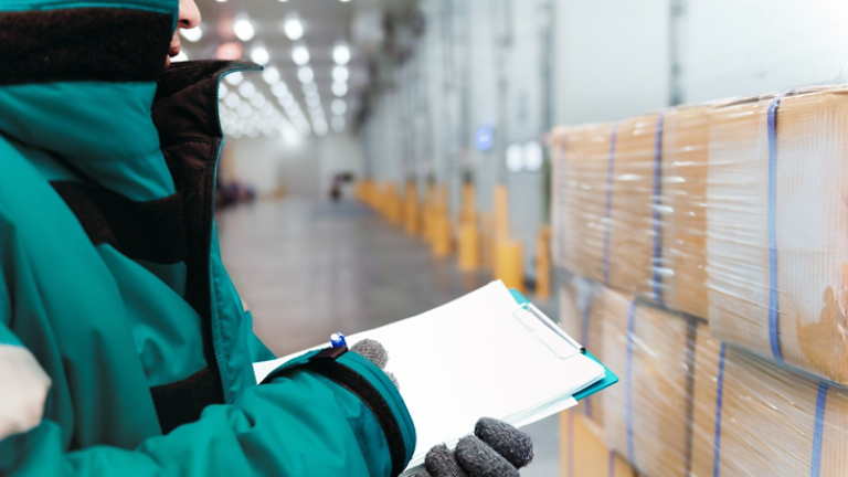 Hand of worker with clipboard checking goods in freezing room or warehouse. Export-Import Logistics system concept