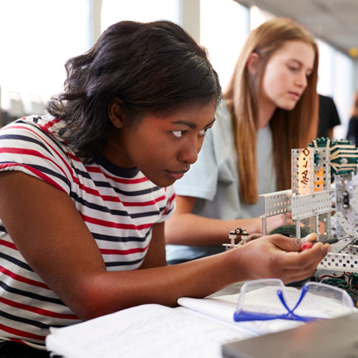 Two Female College Students Building Machine In Science Robotics Or Engineering Class