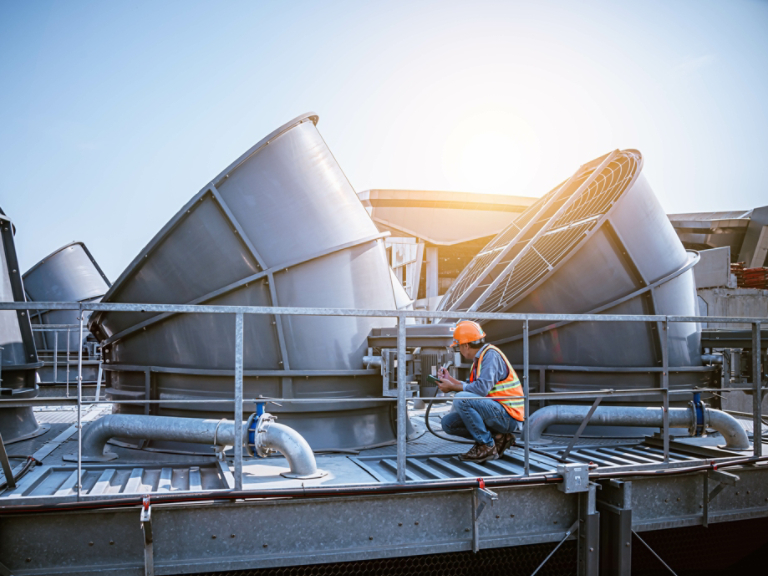 A engineer under checking the industry cooling tower air conditioner is water cooling tower air chiller HVAC of large industrial building to control air system.