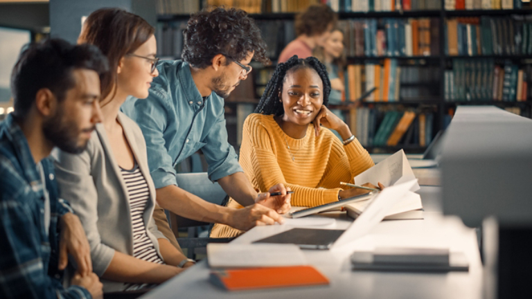 University Library: Diverse Group of Gifted Students Have Discussion, use Laptop, Prepare for Exams Together, Helping, Researching Subjects for Paper Assignment. Happy Young People Study for Future