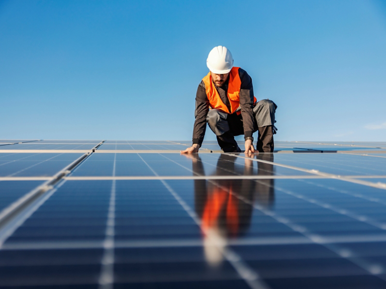 A handyman installing solar panels on the rooftop.