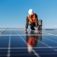 A handyman installing solar panels on the rooftop.