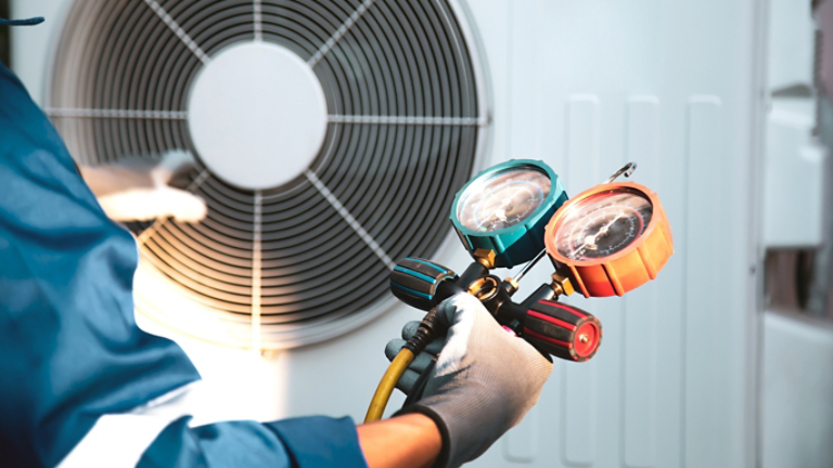 Mechanic air conditioner technician using manifold gauge checking refrigerant for filling home air conditioning and air duct cleaning and maintenance outdoor compressor unit.