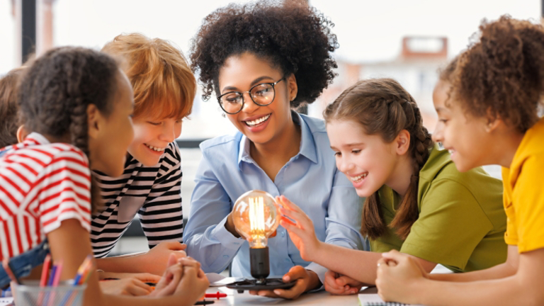 Children gathered around glowing light bulb experiment
