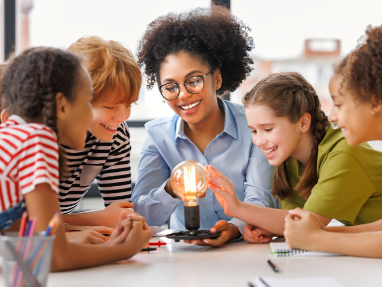 Children gathered around glowing light bulb experiment