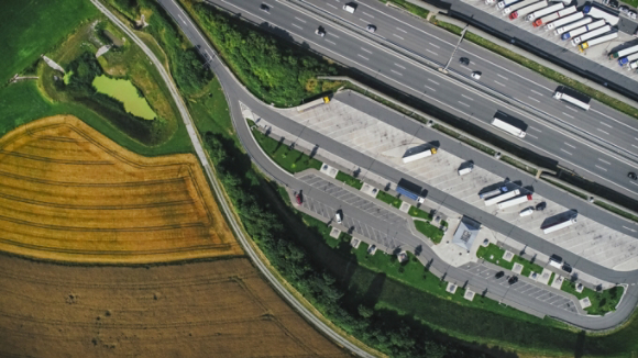 Semi-trucks parked at truck stop next to cultivated land