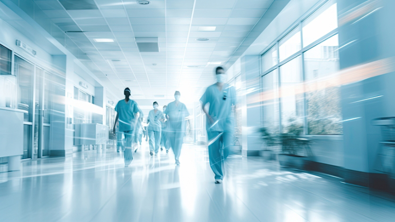 Blurred in motion hospital corridor with running doctors in uniform.