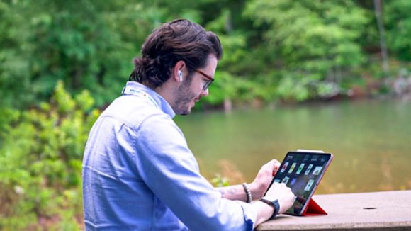 Pablo working on a tablet outdoors by the lake