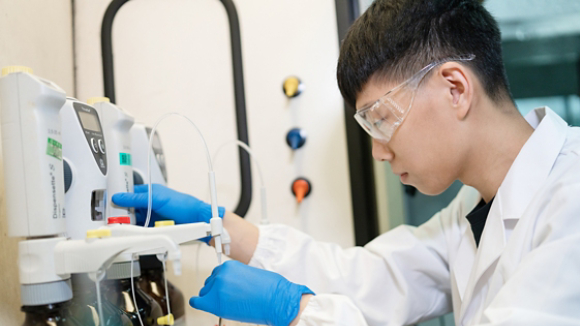 Male lab engineer adding chemicals to beaker 