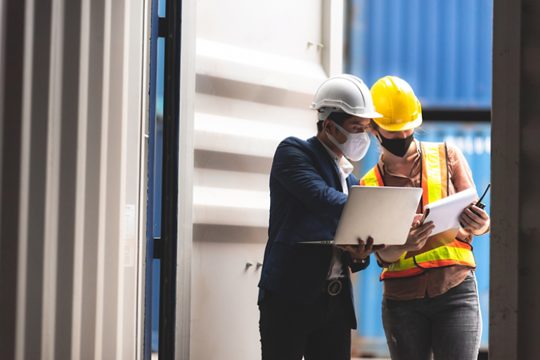 Executive and manager inspecting shipping container