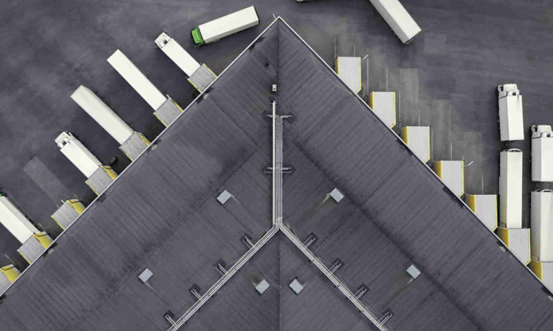 Aerial view of a large distribution warehouse with loading docks and many trucks.