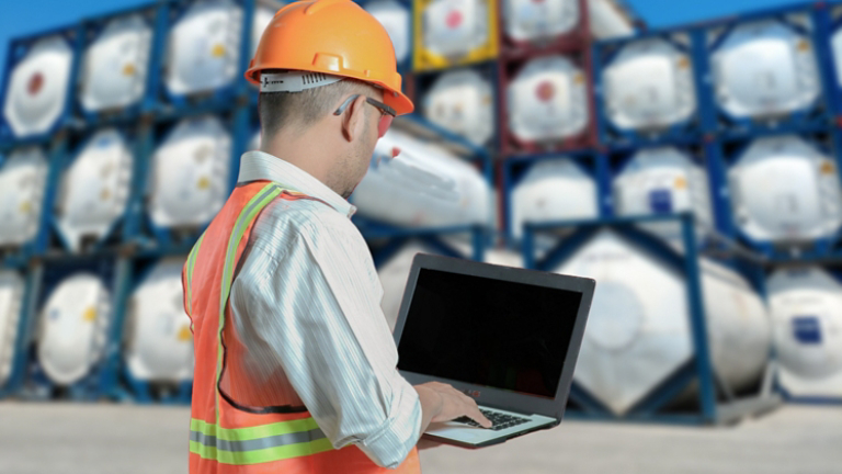 ISO tank : a male officer wearing a safety uniform carrying a laptop checked the condition of the containers at containers freight area.