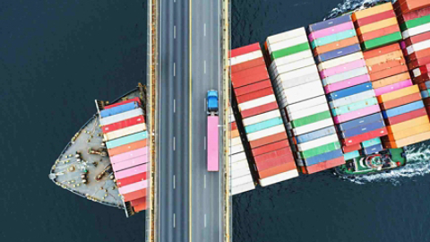 aerial view of cargo ship crossing under a bridge