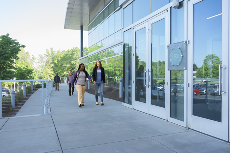 Four employees walking outside of office building