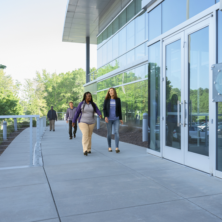 Four employees walking outside of office building