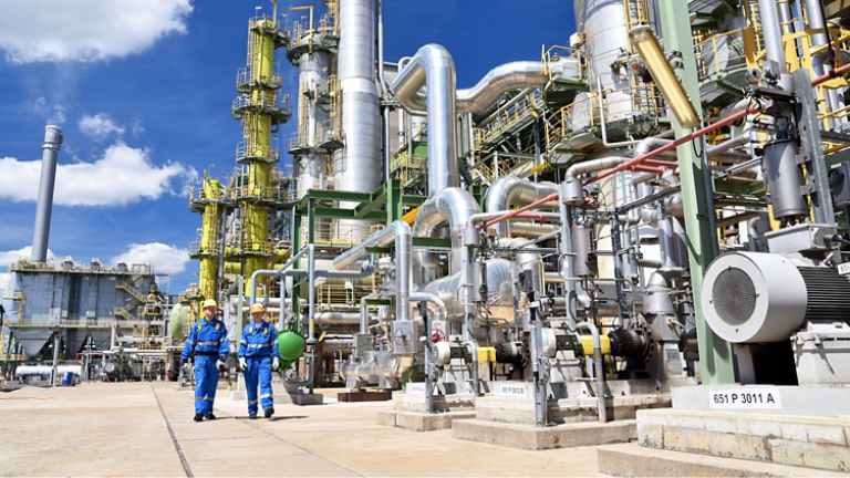 chemical industry plant - workers in work clothes in a refinery with pipes and machinery 
