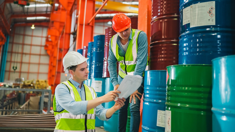 Industrial engineers inspect liquid storage drums in large-scale warehouse for export logistics, ensuring safety compliance, shipping standards, quality control of materials
