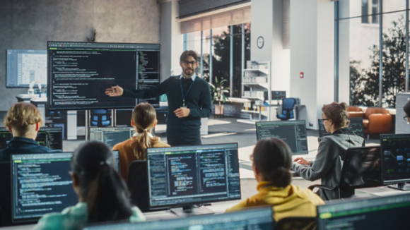 Knowledgeable Teacher Giving a Lecture About Software Engineering to a Group of Smart Diverse University Students. International Undergraduates Sitting Behind Desks with Computers