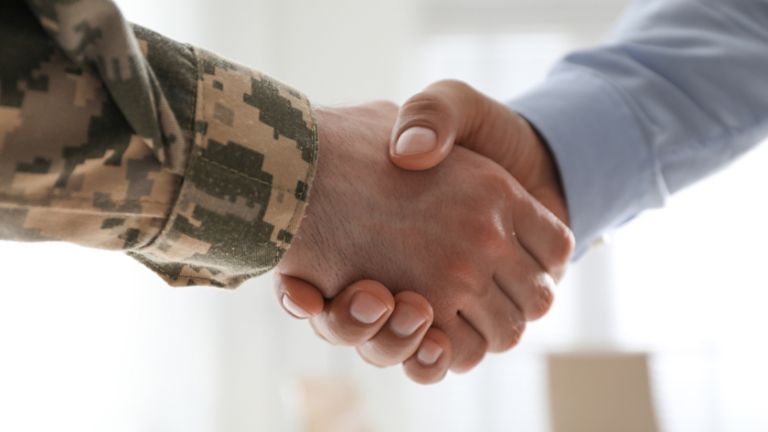 Soldier and businessman shaking hands indoors, closeup
