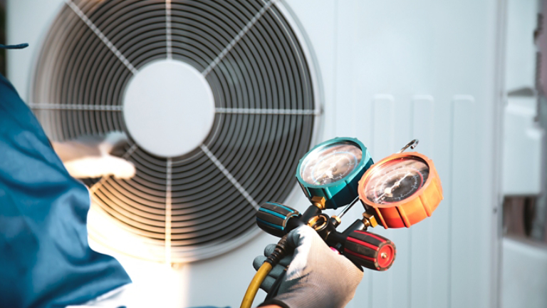 Mechanic air conditioner technician using manifold gauge checking refrigerant for filling home air conditioning and air duct cleaning and maintenance outdoor compressor unit.