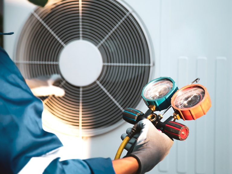 Mechanic air conditioner technician using manifold gauge checking refrigerant for filling home air conditioning and air duct cleaning and maintenance outdoor compressor unit.