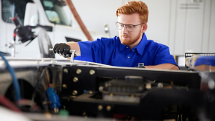 Service technician with socket wrench, servicing truck TRU