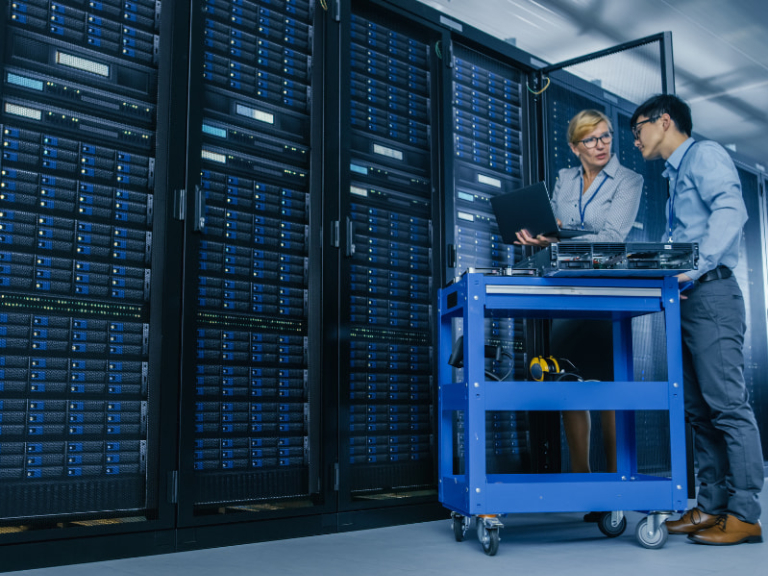 Medium shot of female technician working on a tablet in a data center full of rack servers running diagnostics and maintenance on the system