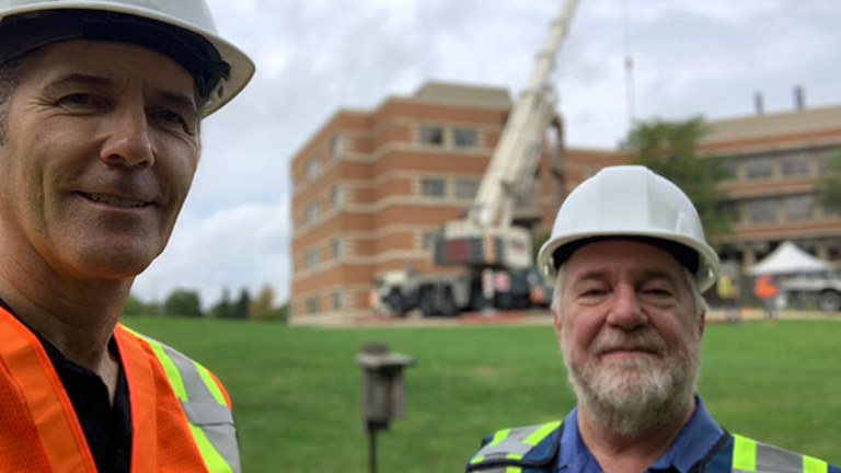 Two builders in front of a crane lift