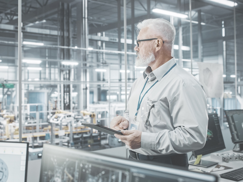 Car Factory Office: Portrait of Successful Caucasian Male Chief Engineer Using Tablet Computer in Automated Robot Arm Assembly Line Manufacturing High-Tech Electric Vehicles. Side View Shot