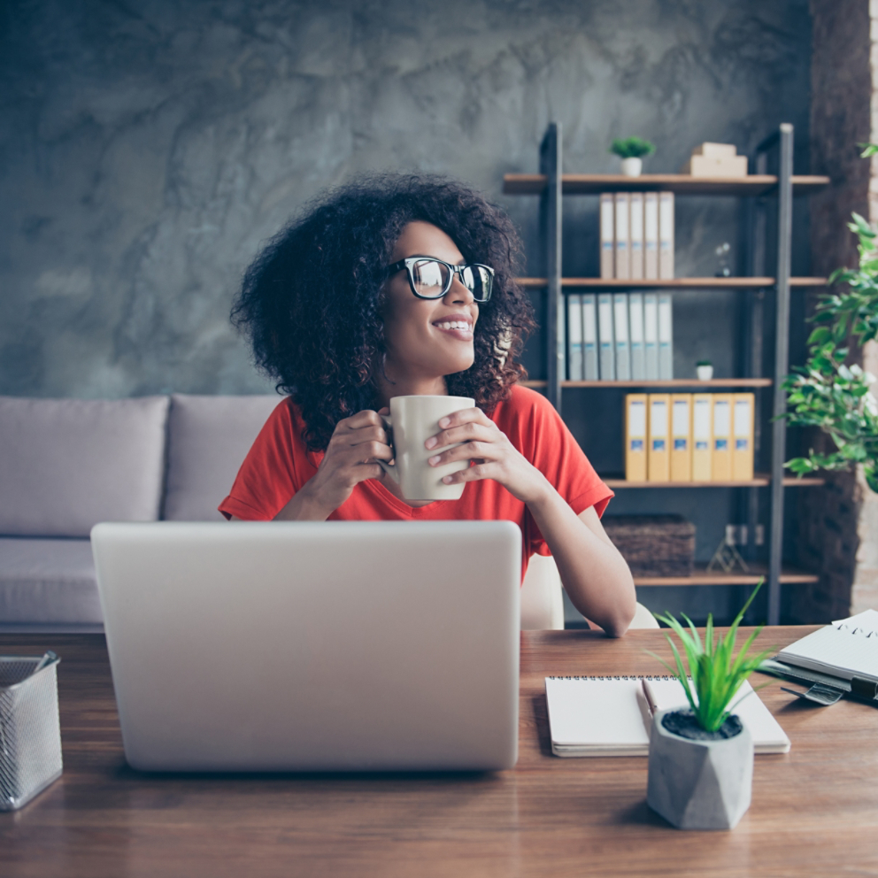 Portrait of dreamy lovely accountant sitting at desk in modern office with interior drinking hot beverage holding cup with tea in hands looking at window enjoying freetime