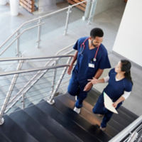 Two healthcare colleagues talking on the stairs at hospital