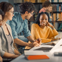 University Library: Diverse Group of Gifted Students Have Discussion, use Laptop, Prepare for Exams Together, Helping, Researching Subjects for Paper Assignment. Happy Young People Study for Future