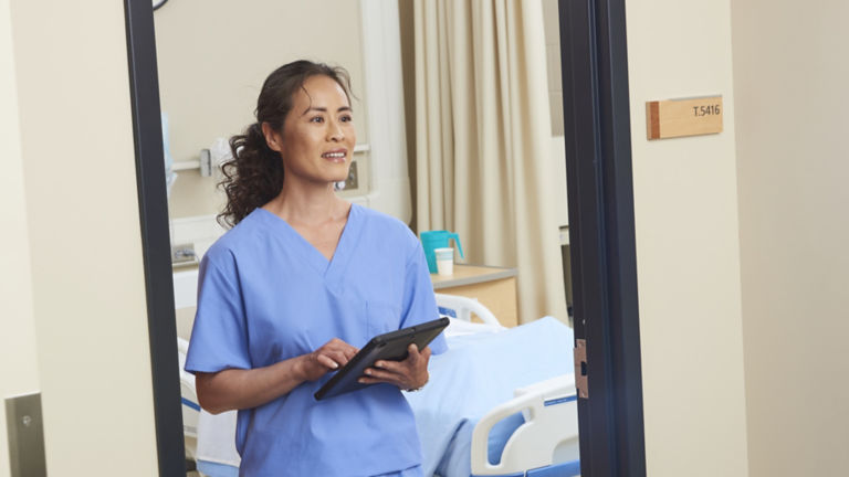 Nurse in Hospital Room with Tablet