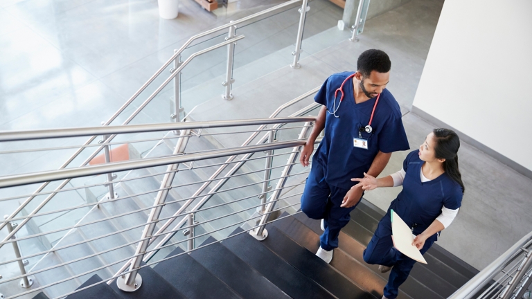 Two healthcare colleagues talking on the stairs at hospital