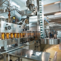 Conveyor belt or line in beverage plant with modern automated industrial machine equipment. Plastic PET bottles with fresh organic juice in factory interior