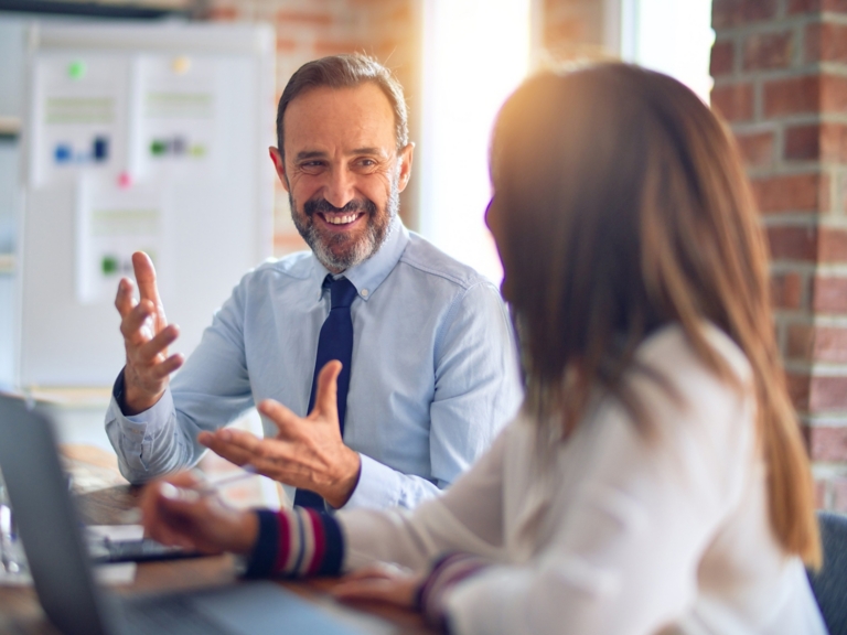 Two middle age business workers smiling happy and confident. Working together with smile on face using laptop at the office