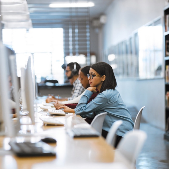 The student life. Shot of a group of university students working on computers in the library at campus.