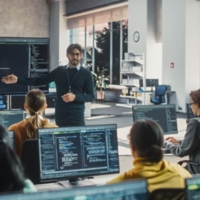 Knowledgeable Teacher Giving a Lecture About Software Engineering to a Group of Smart Diverse University Students. International Undergraduates Sitting Behind Desks with Computers