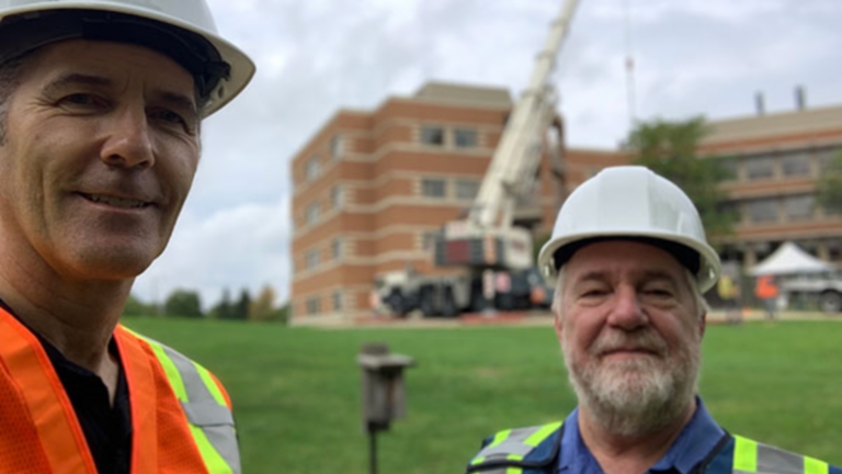 Two builders in front of a crane lift